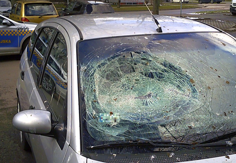 Rozbita przednia szyba w fordzie zaparkowanym na Bródnie. W tle radiowóz straży miejskiej. 
