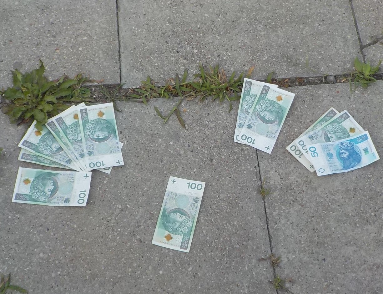 STu- i pięćidziesięciozłotowe banknoty rozłożone na płytach chodnikowych.
