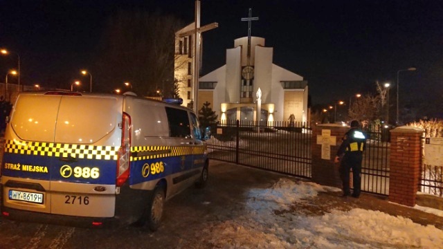 Radiowóz straży miejskiej przed bramą kościoła
