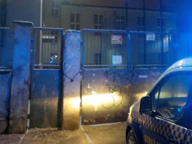 Radiowóz straży miejskiej przed bramą szkolną, gdzie utknął nastolatek