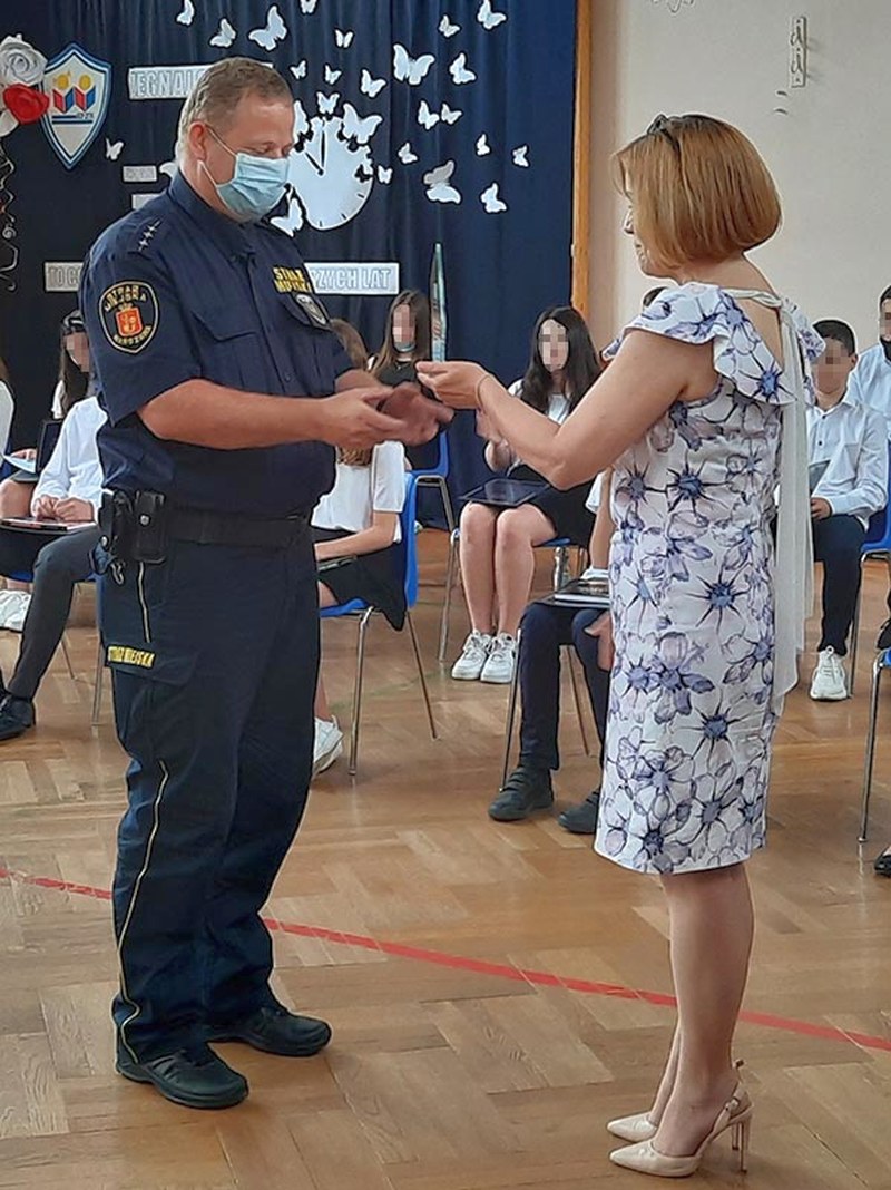 Dyrektor szkoły wręczająca nagrodę starszemu inspektorowi Krystianowi Senkulskiemu