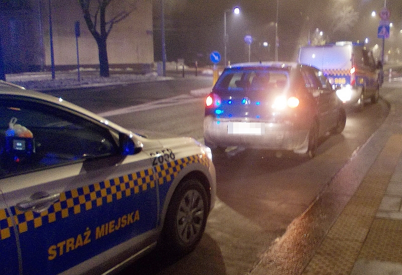 Zdjęcie z interwencji: radiowóz straży miejskiej stoi za zatrzymanym na jezdni volkswagenem.