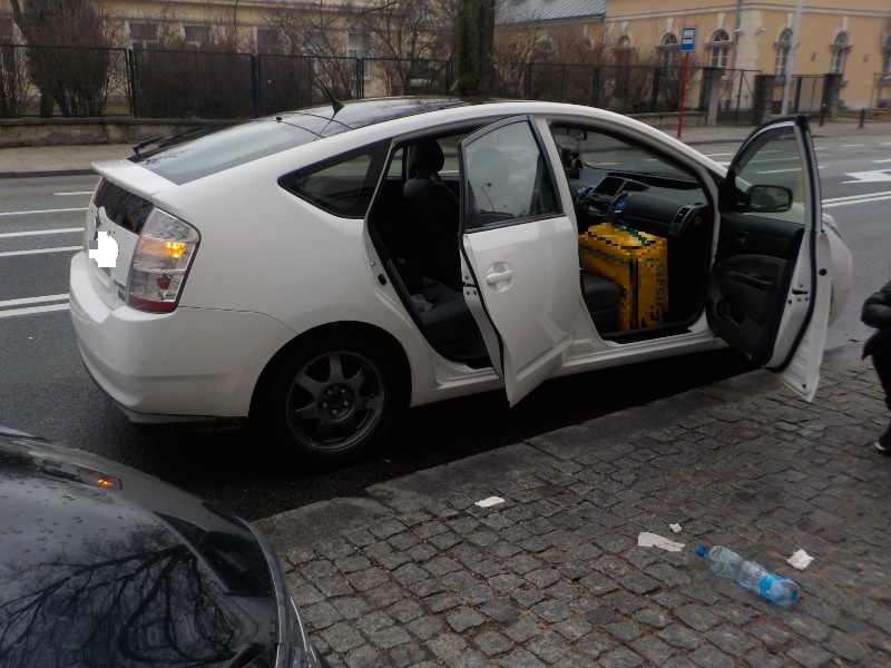 Zdjęcie z interwencji: biały samochód stoi na poboczu jezdni z uchylonymi drzwiami od strony pasażera z tyłu i przodu. W przednich drzwiach widoczna żółta torba kurierska.