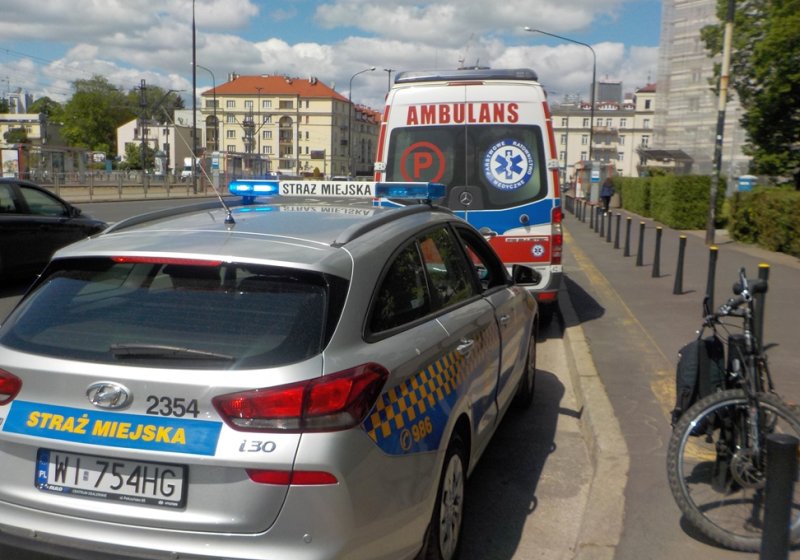 Radiowóz straży miejskiej ustawiony za karetką pogotowia na skraju jezdni.