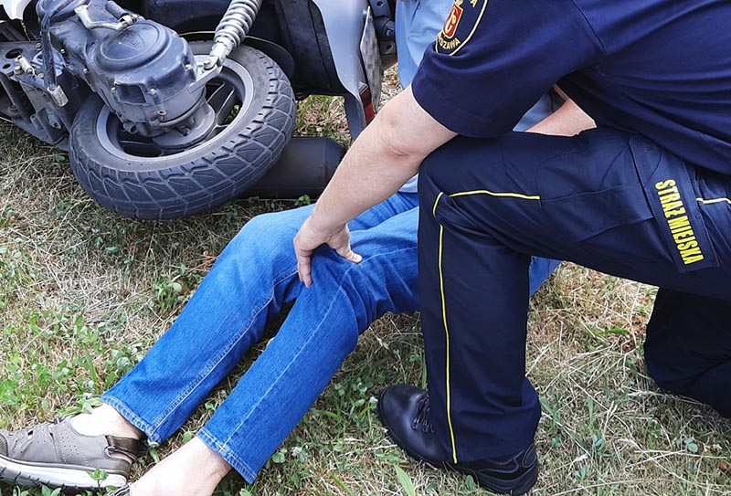 Strażnik przy leżącym obok przewróconego skutera mężczyźnie - zdjęcie ilustracyjne