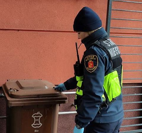 Zdjęcie ilustracyjne: strażniczka miejska przy koszu na bioodpady.