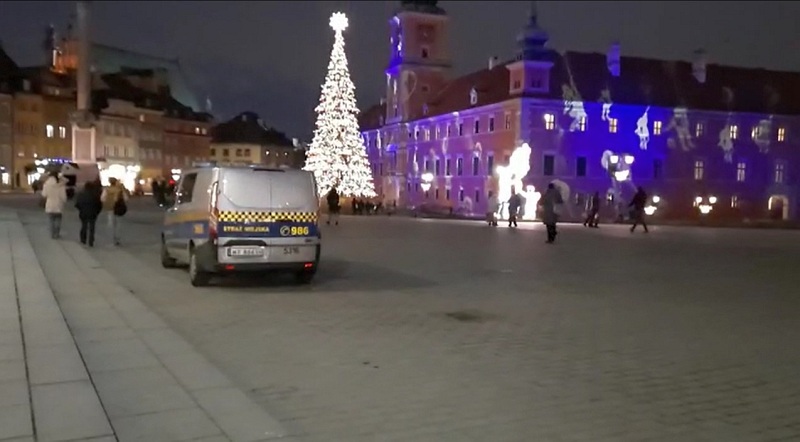 Zdjęcie ilustracyjne: radiowóz straży miejskiej na tle świątecznej iluminacji Zamku Królewskiego i choinki.