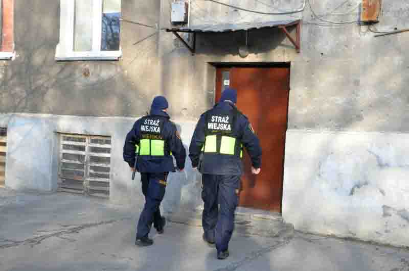 Zdjęcie ilustracyjne: strażnicy miejscy wchodzący do klatki schodowej.