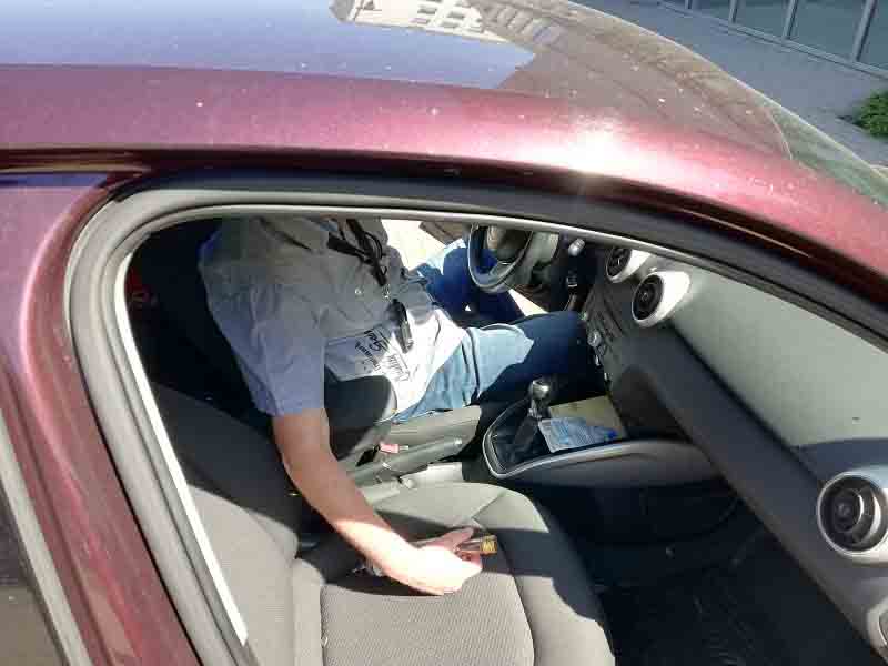 Zdjęcie ilustracyjne: widok od drzwi pasażera: mężczyzna siedzący za kierownicą samochodu z butelką alkoholu w prawej ręce.