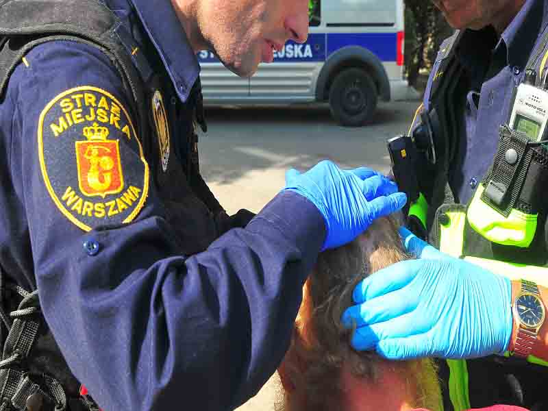 Strażnik miejski opatrujący głowę rannemu- zdjęcie ilustracyjne.