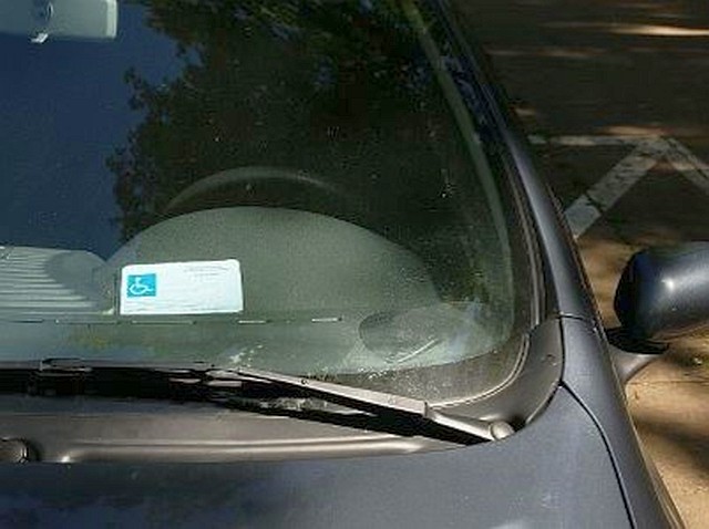 Zdjęcie przedstawiające prawidłowe eksponowanie karty parkingowej: za przednią szybą pojazdu samochodowego, w miejscu widocznym, tak, by możliwe było odczytanie jej numeru i daty ważności.