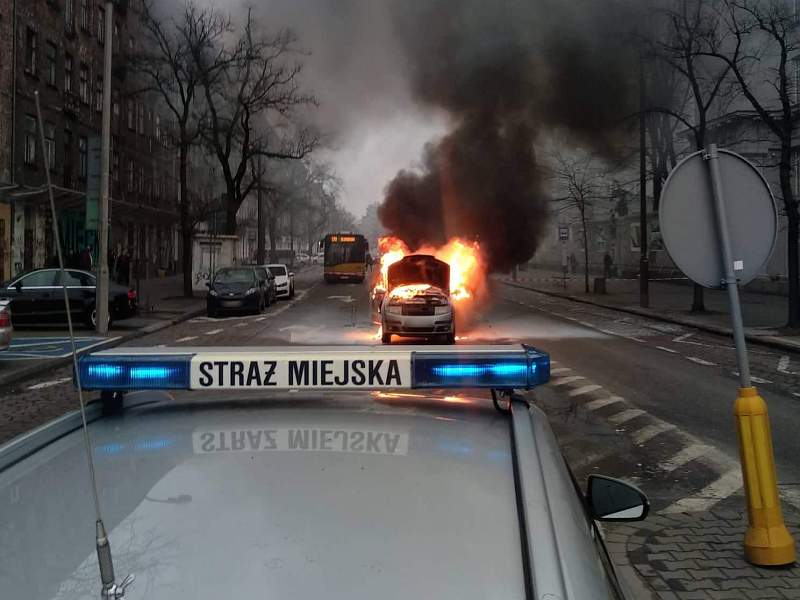 Skoda płonąca przy Wileńskiej. Na pierwszym planie radiowóz Straży Miejskiej