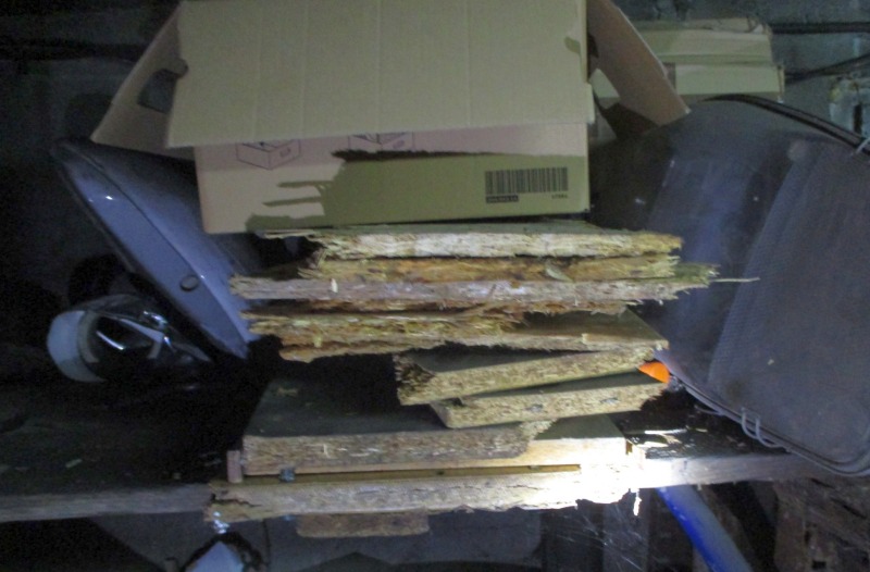 Zdjęcie z interwencji: na półce leżą fragmenty połamanych płyt pilśniowych przemieszanych z kartonami, przygotowane do spalenia w piecu.