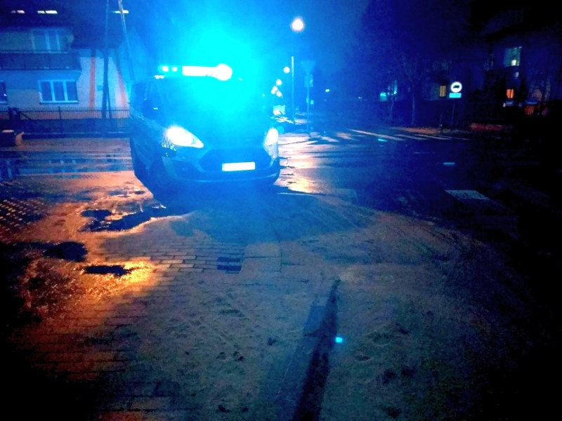 Zdjęcie z interwencji: radiowóz straży miejskiej zabezpieczający miejsce zdarzenia. Przed nim, na chodniku, widoczna dziura między kostkami brukowymi.