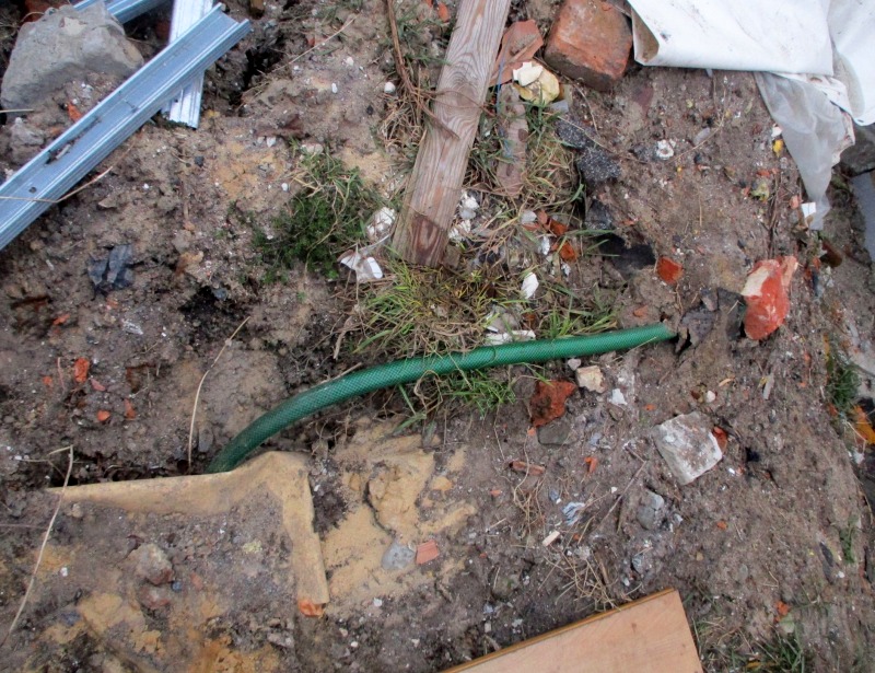 Zdjęcie z interwencji: teren, z którego wyprowadzony był wąż z szambem. Wokół leży gruz, śmieci  stare cegły.
