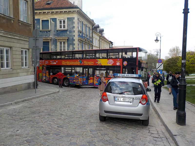 Zdjęcie z interwencji: radiowóz straży miejskiej zabezpiecza miejsce zdarzenia. W tle autobus, który zablokował skrzyżowanie.