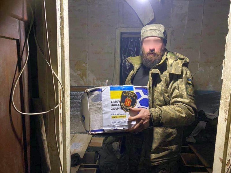 Ukraiński żołnierz niesie karton z darami.