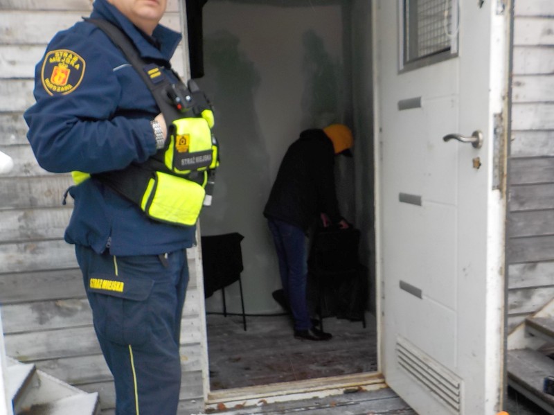 Strażnik miejski przed drzwiami budynku, w którym zamieszkał mężczyzna